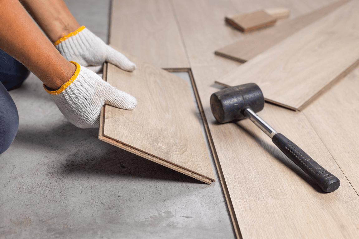 Handwerker verlegt hellen Laminatboden — Renovierungsarbeiten in Berlin